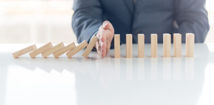 Businessman Stop Domino Effect. Risk Management and Insurance Concept