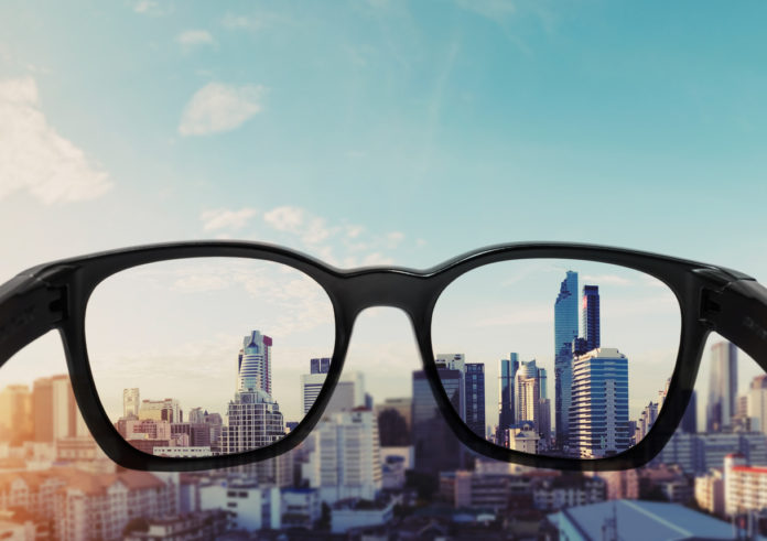 Eye glasses looking to city view, focused on glasses lens