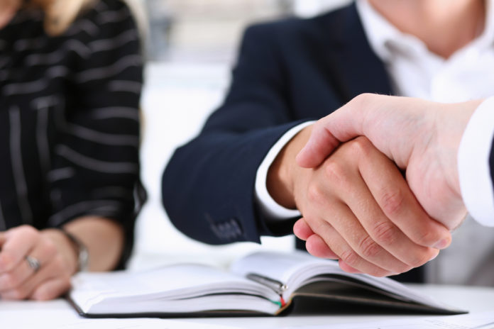 Man in suit shake hand as hello in office closeup