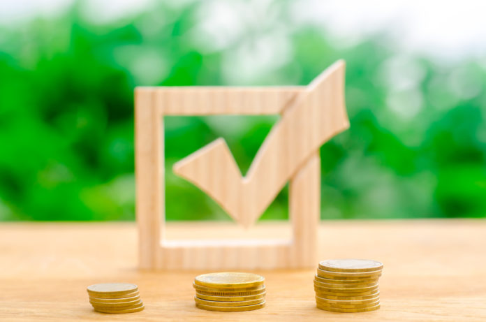 Wooden check mark and stacks of coins. Interest rates on deposits and loans. Lobbying the adoption of regulations and laws. Illegal money laundering and control of financial flows. Selective focus