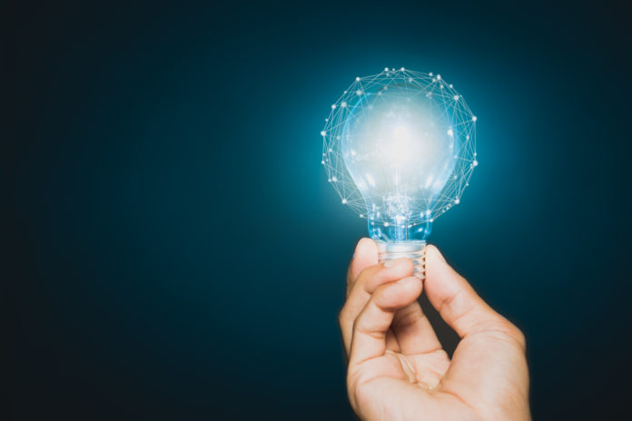 Hand of businessman holding illuminated light bulb, idea, innovation and inspiration concept.