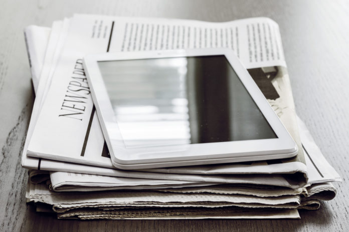 Newspaper and digital tablet on wooden table