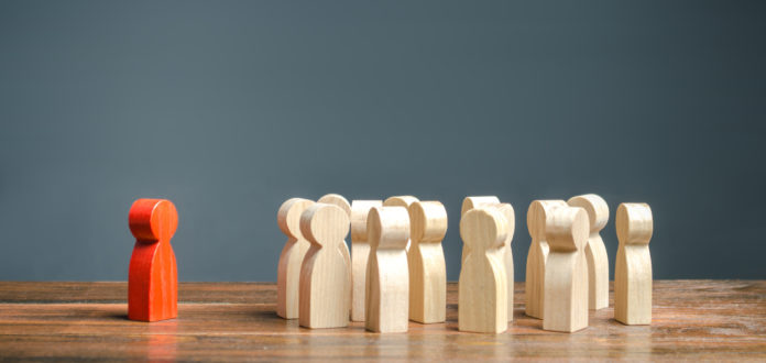 red figurine of a man stands aside from the crowd of people. Asociality, sociopathy. Rejected from society, lonely. Development of leadership and social qualities. Infected, fear and misunderstanding.