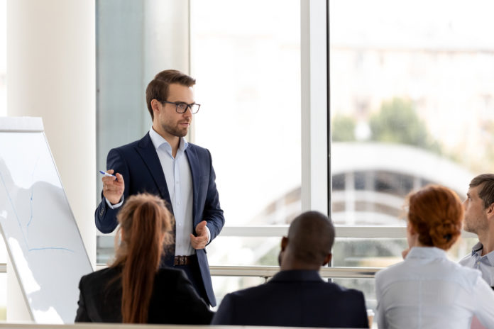 Successful millennial businessman boss presenting new project to employees