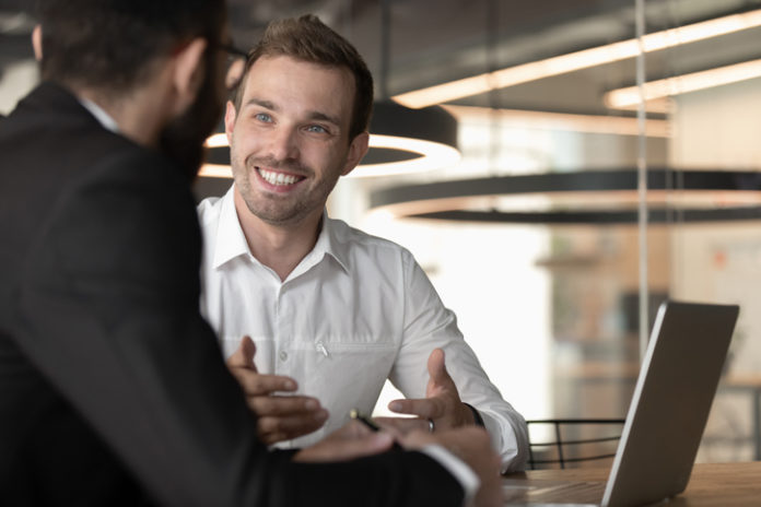 Smiling Caucasian businessman talk cooperating with male colleague