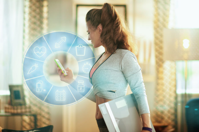 sports woman with smart scale tracking weight in a fitness app