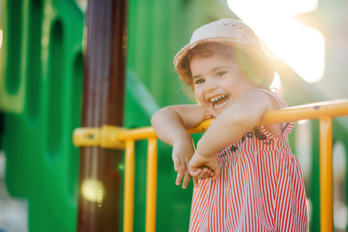 Little Cute Girl With Hat Playing At Playground Outdoors In Summer