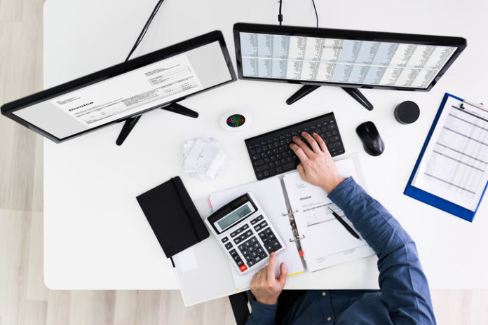 Young Businessman Calculating Bill In Office