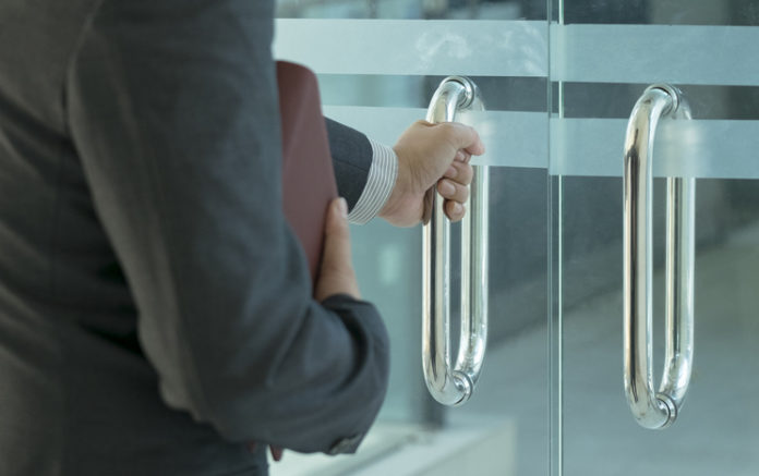 Businessman entering an office by opening out a glass door