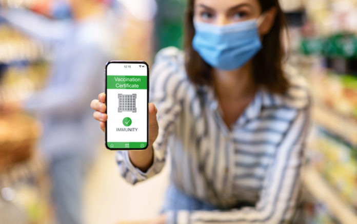 Young woman showing smartphone with digital health passport in store