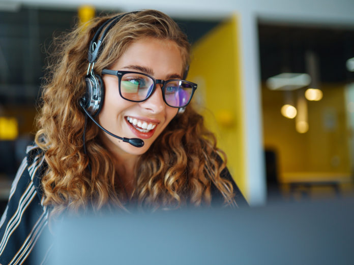 Young operator woman with headsets working in a call centre.
